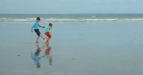 Two young boys runnong afor a soccer beach ball. Vídeo Stock 79794055