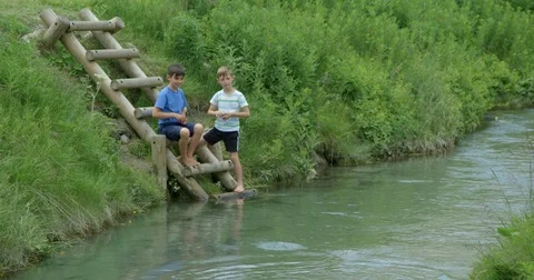 Two young boys throwing stones into a river. 스톡 동영상 78027673