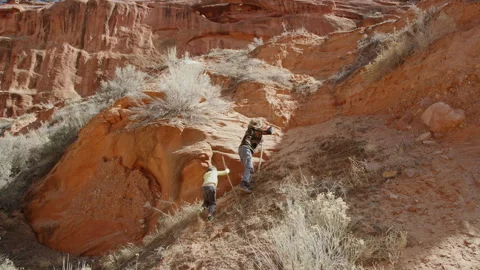 Two young boys try to climb steep and sandy Escalante red rock mountainside Stockbeeldmateriaal 248581204