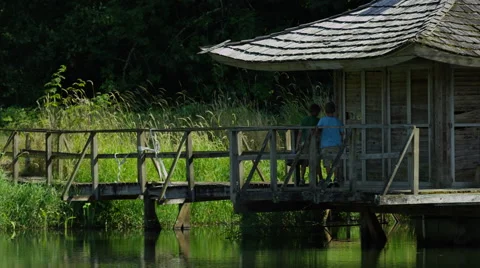 Two young boys walking on dock at lake Stock Footage