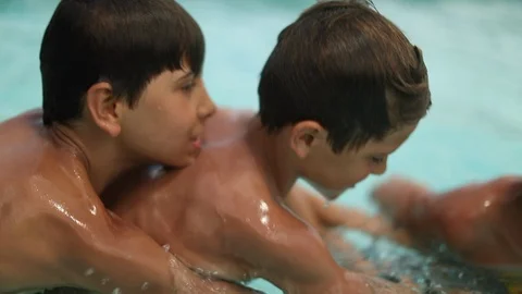 Two young brothers competing each other at swimming pool. Kids playing and fi Video stock 128799575