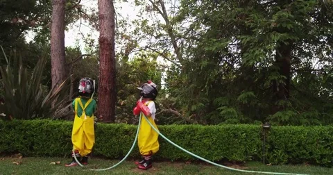 Two young brothers dressed as firemen team up to control a garden hose's stream. Stock Footage 69188220