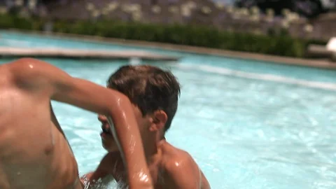 Two young brothers fighting each other in competition at the swimming pool. K Video stock 128799727
