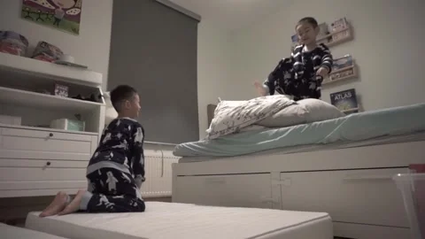 Two young brothers jumping off the bed, slow motion Stock Footage 226723619