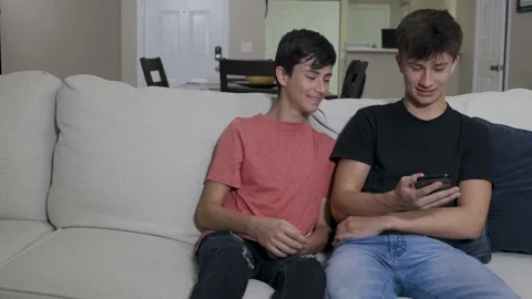 Two young brothers looking at a mobile device cell phone laughing and smiling Stock Footage 137274686