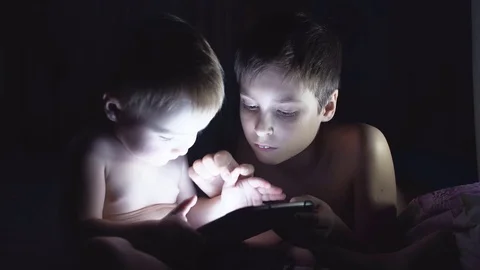 Two young brothers playing with tablet at night. 4K Stock Footage 70706420