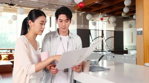 Two young business people looking through financial documents discussing work Stock Footage 328748481