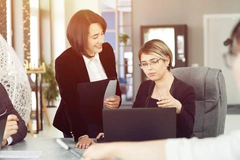 Two young business women in the office, analyzing information looking into a Stock Photos