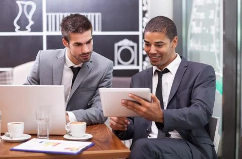 Two young businessman working on a digital tablet in a cafe Stock-Fotos