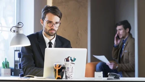 Two Young Businessmen. One of Them is Showing a Paper to His Partner Stock Footage 70914614