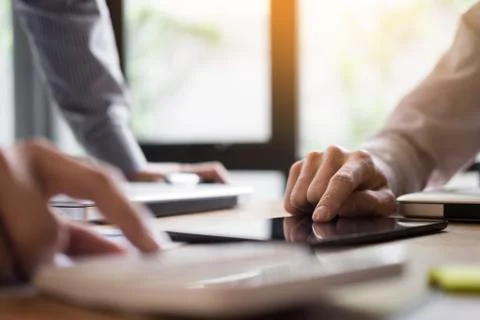 Two young businessmen using touchpad explaining his business plans to his col Stock Photos
