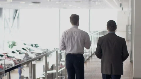 Two young businessmen walking through the gallery in autocenter, slow motion. Stock Footage 88408367