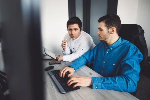Two young caucasian programmers working on desktop computers in the office Stock Photos