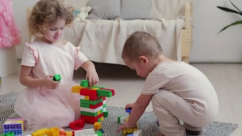 Two young children are engaged in play with colorful building blocks on the Vídeos de archivo 336460055