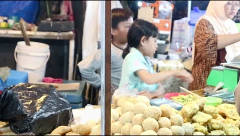 Two young children help their mother serve customers at the night market Stock Footage 302773320