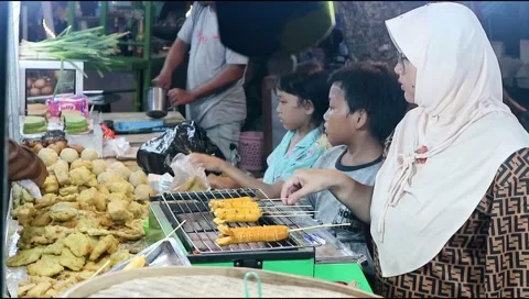 Two young children help their mother serve customers at the night market Stock Footage 302773366