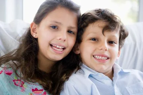 Two young children in living room smiling (high key) Stock Photos