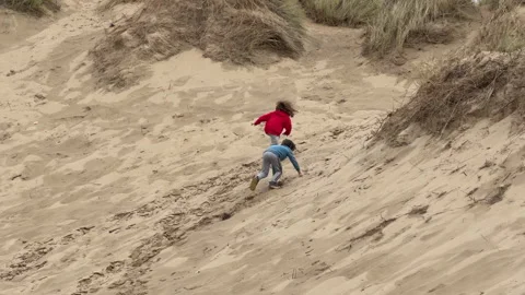 .Two young children make their way to the top of a sand dune in Formby Vidéo 312914411