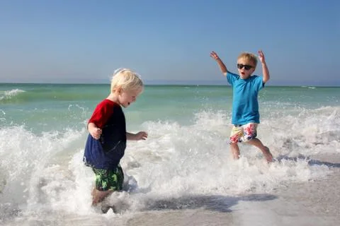 Two young children playing and splashing in ocean water Stock Photos