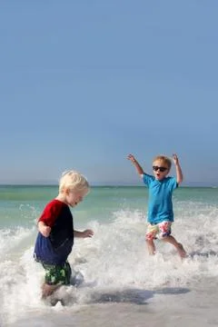 Two young children playing and splashing in ocean water Stock Photos