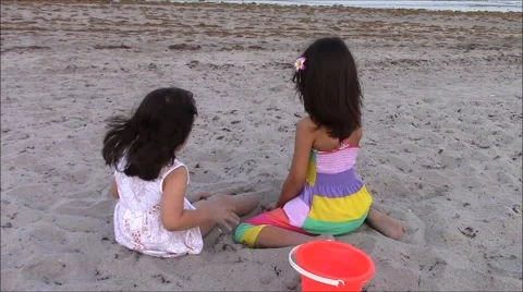Two Young Children Playing with Sand on the Beach Stock Footage 49970490