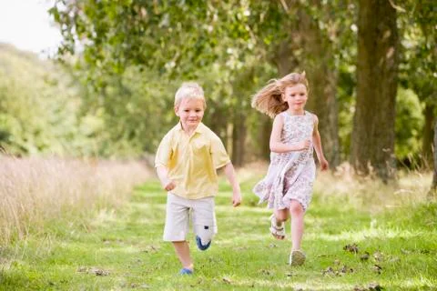 Two young children running on path smiling Foto stock