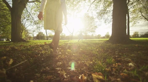 Two young children walking and running into a wide area play park on a sunny day Stock Footage