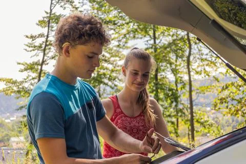 Two young climbers talking and taking gear out of the car Stock Photos