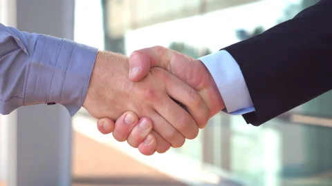 Two young colleagues shaking hands after successful deal near office building Stock Footage 98197874
