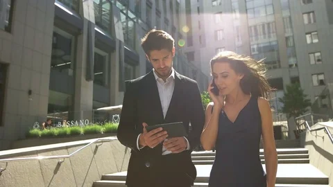 Two young colleagues walking on stairs, woman talking on phone, man using tablet Stock Footage 73813163