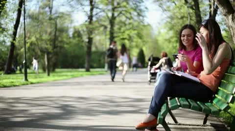 Two young college friends using a smart phone, outdoors, tracking shot HD 스톡 동영상 11054373