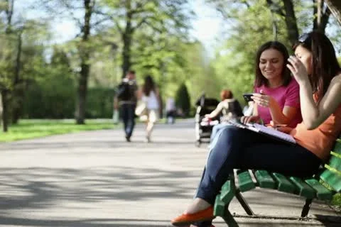 Two young college friends using a smart phone, outdoors, tracking shot NTSC Stock Footage 11054441