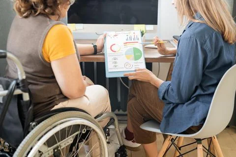 Two young contemporary female economists discussing financial papers with charts Stock Photos