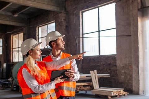 Two young contemporary technicians in protective helmets Stock Photos