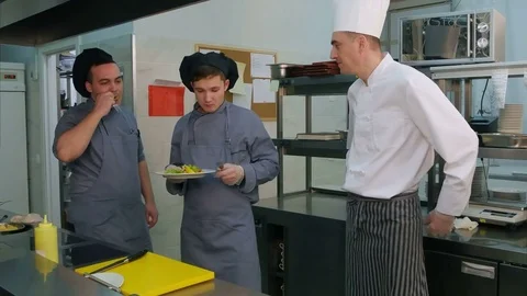Two young cook trainees enjoying shrimp salad cooked by chef Vídeos de archivo 72321576