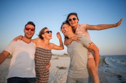 Two young couples admire a sunset on the sea coast. Stock Photos