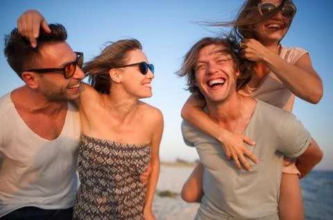 Two young couples admire a sunset on the sea coast. Stock Photos