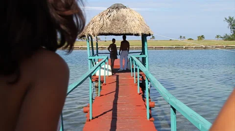 Two young couples meet on Tiki Hut on pier over water Stock Footage 38762021