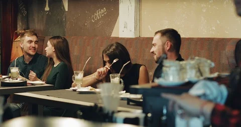 Two young couples rest in a cafe in the evening. Stock Footage 94477562