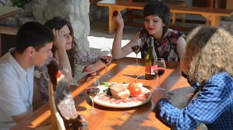 Two young couples sitting, talking, laughing and enjoying some food and drinks Vidéo 55312884