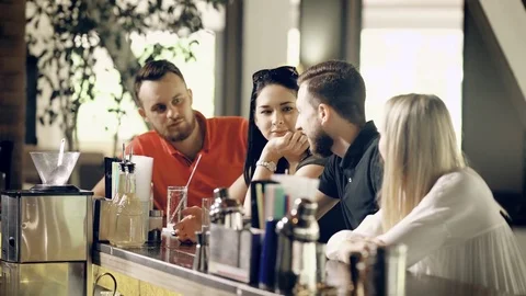 Two young couples spend time in a modern bar, a group of friends are having fun Stock Footage 77998312