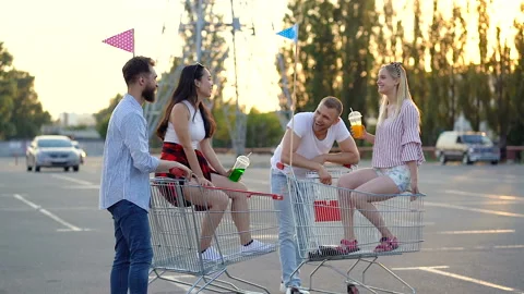 Two young couples standing at the car parking with supermarket trolleys. Stock Footage 109614727