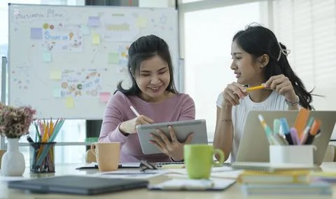 Two young creative designers brainstorming and discussing new startup project Stock Photos