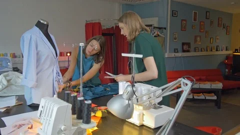 Two young creative tailors talking and working in small fashion studio. Stock Footage 80471568