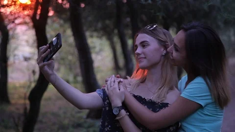 Two young cute sisters doing selfie in the forest at sunset Video stock 100750130