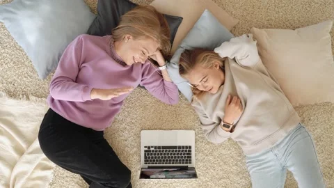 Two young cute sisters lying on the floor at home and watching movie on laptop Stock Footage 150518708