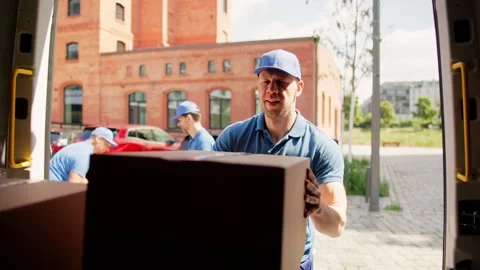 Two young delivery men loading cardboard boxes in a truck for a moving service Stock Footage 278697249