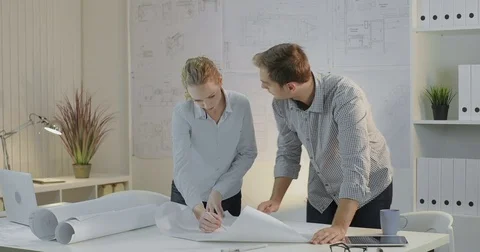 Two young designers discuss the project drafted on paper of large format Stock Footage 81667915