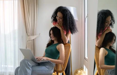 Two young diverse women using laptop togehter at home Stock Photos