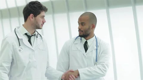 Two young doctors engage in a professional handshake Stock Footage 311674766